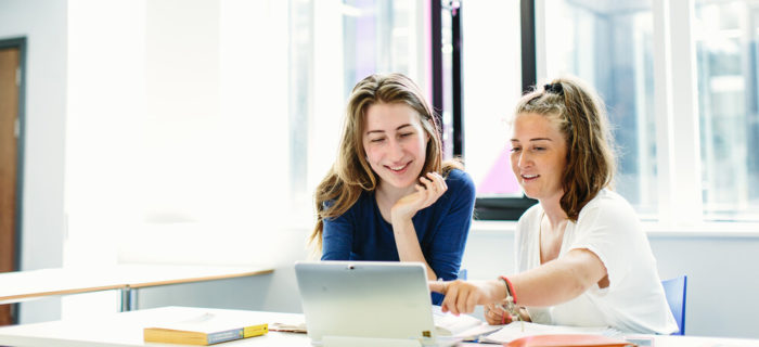 Two students look at a tablet screen.