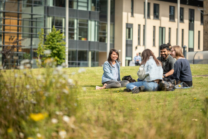 Students sat on a field on a sunny day
