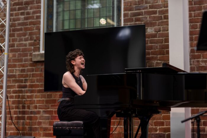 A woman is singing and playing the piano.